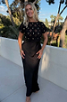 Black Crochet Shell Elodie Dress with gold knit details and a satin skirt, highlighting inclusive sizing on a balcony.