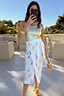 Thumbnail for White Shells Jaspre Wrap Skirt featuring a shell print and wrap tie, styled with a gold top for a vacation look.