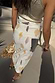 Thumbnail for Shells Jaspre Wrap Skirt in white with a golden shell print, paired with a metallic top and straw fringe bag.