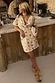 Thumbnail for Cream Shell Mini Wrap Dress with multi-coloured seashell motifs and a wrap tie, styled for a summer vacation.