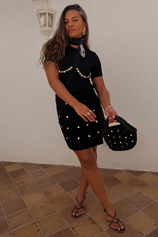 Black Crochet Shell Wrap Skirt with gold shell details and a tie waist, styled with strappy sandals.