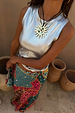Metallic silver ribbed tank top styled with a colourful patterned skirt and statement sun necklace.