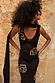 Black & Gold Simona Sequin Dress in sheer mesh with gold motifs and a detachable scarf against a stone wall.