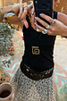 Deloris Mermaid Necklace with an engraved brass pendant on an adjustable leather cord, worn with a leopard skirt.