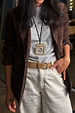 Deloris Mermaid Necklace featuring an engraved brass pendant on a black leather cord, styled over a brown blazer.