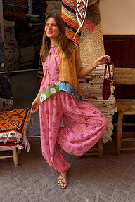 Pink Snake Balloon Trousers with snake and swirl motifs, styled with a patchwork top in a rustic textile market.
