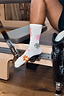 White cotton Element crew socks with colourful graphic prints, worn by a model on a Pilates reformer.