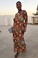 Brown Star Fawn Aria Mesh Dress with sun, star and palm motifs, flared sleeves and a sheer midaxi silhouette.