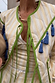 Close-up of the Butter Yellow Stripe Quilted Jacket with green trim, blue tassels and multiple tie-front fastenings.