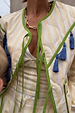 Close-up of the Butter Yellow Stripe Quilted Jacket with green trim, blue tassels and multiple tie-front fastenings.