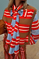 Multi Stripe Tie Shirt in blue and red cotton with a multi-wear bow, layered under a striped knit vest for a London look.