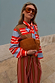 Multi Stripe Tank Top in tan and red knit, layered over a striped shirt with a bow and matching striped trousers.