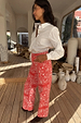 White cotton Marley Shirt with gold studs on the sleeves, styled with red bandana jeans for a bold London look.