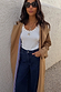 White Studded Rib Vest with gold stud detailing, styled with a camel trench coat and dark denim jeans.
