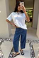 White Studded T-Shirt with silver neck studs and relaxed fit, styled with blue wide-leg jeans in a mirror selfie.