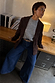 Premium Chocolate Suede Jacket in brown, layered with a grey knit and wide-leg denim for a transeasonal look.