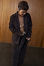 Thumbnail for Chocolate Suede Jaspre Skirt being tied at the waist, styled with a matching blazer and gold jewellery.