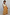 Thumbnail for Yellow cotton maxi dress with an orange sun print and shirred waist on a girl against a white wooden wall.