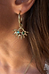 Gold-tone Deloris Sun Hoop Earrings featuring iconic sun motifs and semi-precious stones, worn on the ear.