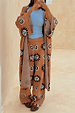 Tan Sun Trousers in a knit sun print, rolled at the waist and styled with a matching cardigan and blue top.