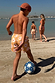 Boy's Yellow Sun Swim Shorts with a white and orange sun print, worn while playing football on a beach vacation.