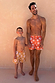 Boy's Yellow Sun Swim Shorts with a white sun print, worn by a boy and man for a matching family vacation look.