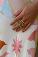 Deloris Sun Ring in brass featuring an iconic sun motif and semi-precious stones, worn on a hand.