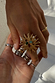 Deloris Sun Ring in brass featuring a sun motif and semi-precious stones, styled with layered jewellery on a hand.
