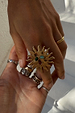 Deloris Sun Ring in brass featuring a sun motif and semi-precious stones, styled with layered jewellery on a hand.