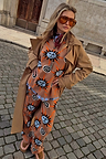 Tan Sun Copenhagen Jumper with sun and swirl motifs, styled with matching trousers and a long camel trench coat.