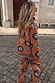 Thumbnail for Tan Sun Copenhagen Jumper and matching trousers featuring sun and swirl motifs on a cobblestone street.
