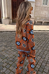 Tan Sun Copenhagen Jumper and matching trousers featuring sun and swirl motifs on a cobblestone street.