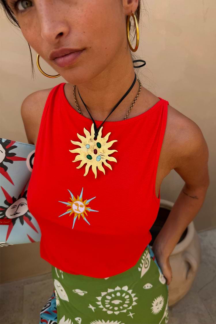 Orange Sun Twisted Strap Tank in ribbed jersey with an embroidered sun motif, gold necklace and green skirt.
