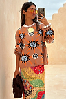 Tan Sun Copenhagen Jumper in a tan knit with hand-painted sun motifs, styled with a colourful patterned skirt.
