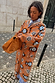 Thumbnail for Tan Sun Cardigan with hand-painted sun motifs and dropped shoulders, styled on a cobblestone street.