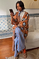 Thumbnail for Tan Sun Cardigan with hand-painted sun motifs and an oversized fit, paired with blue striped trousers.