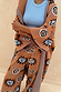Thumbnail for Tan Sun Cardigan with Mediterranean sun motifs, styled as a co-ord with matching trousers and a blue top.