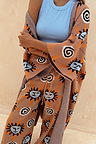Tan Sun Cardigan with Mediterranean sun motifs, styled as a co-ord with matching trousers and a blue top.