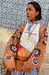 Tan Sun Cardigan featuring Mediterranean-inspired sun motifs and swirls, styled with a graphic tee and blue neckerchief.