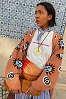 Tan Sun Cardigan featuring Mediterranean-inspired sun motifs and swirls, styled with a graphic tee and blue neckerchief.
