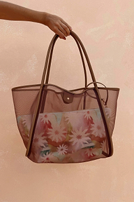 Tan Mesh Tote Bag featuring leather straps and an abstract soleil printed pouch, held against a textured wall.