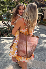 Tan Mesh Tote Bag with leather straps and an abstract soleil print pouch, held by a woman in a vacation setting.