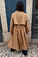 Tan Trench Coat with Gold Studs shown from behind, featuring a storm flap and belted waist in a street setting.