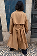 Tan Trench Coat with Gold Studs shown from behind, featuring a storm flap and belted waist in a street setting.