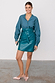 Teal Vegan Leather Mini Jaspre Skirt with a wrap waist, paired with a matching shirt and pink heels.
