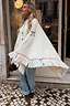 Cream Western Knitted Cape with fringe trim and bow detail, styled with denim for a trans-seasonal London look.