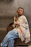 Western Knitted Cape in cream with fringe hem and motifs, styled with jeans and a leopard print bag.