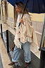 Cream Western Knitted Cape with fringe and western motifs, styled with light-wash jeans and a blue umbrella.