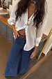 Oversized White Miley Shirt with tortoise buttons and blouson sleeves, styled with wide-leg denim jeans.