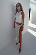 White Ribbed Tank with an embroidered logo, styled with a silver sequin wrap skirt and sunglasses for a vacation look.